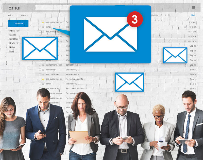 A group of people using computers and paper with email icons