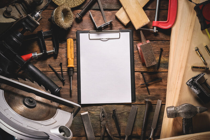 Blank notepad page with copy space and other construction tools on brown wooden table background