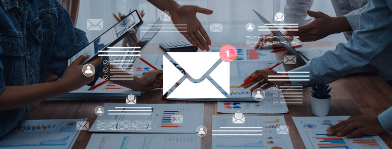 A dynamic team collaborates in an office setting, utilizing digital devices and data analysis to produce an email management strategy.